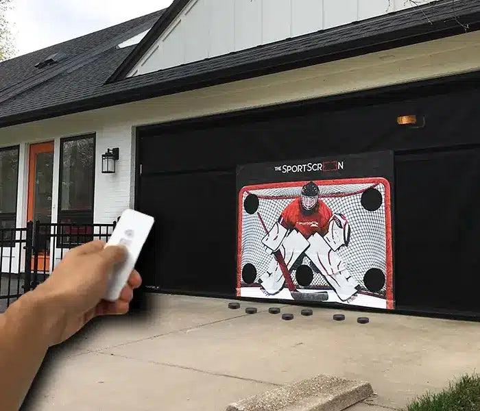 man holding remote in front of 16ft SportScreen showing that you can convert a hand crank sportscreen to remote control