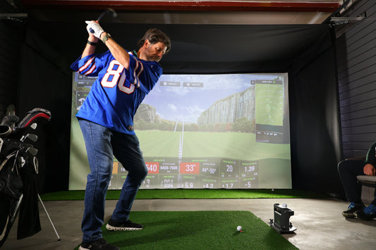 Man golfing in indoor golf simulator enclosure