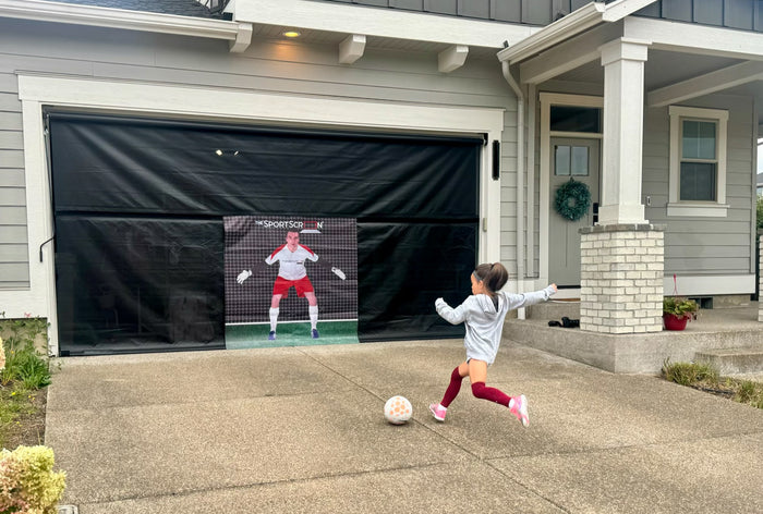 Girl kicking soccer ball on SportScreen in driveway