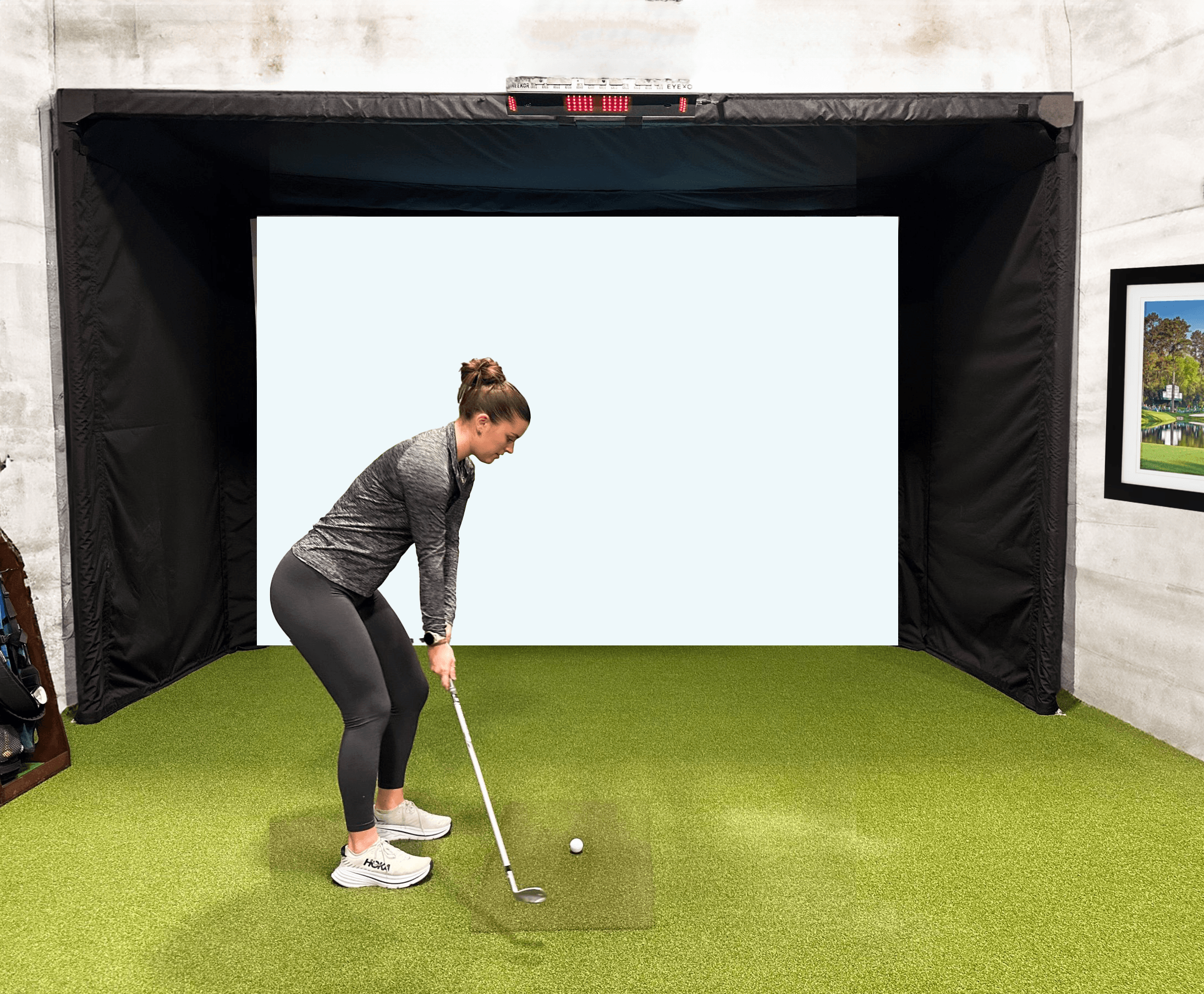 Girl golfing in parlour series 13H with launch monitor mounted to golf sim frame. Girl mid golf swing