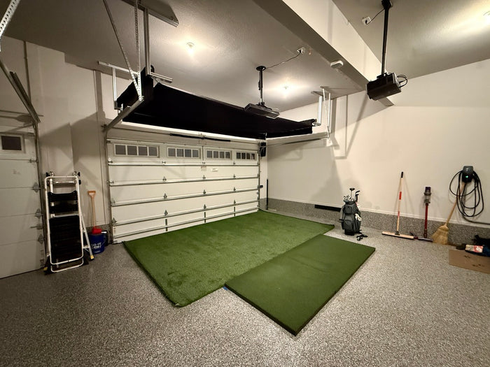 Garage with green mats on the floor and various items including a golf bag.